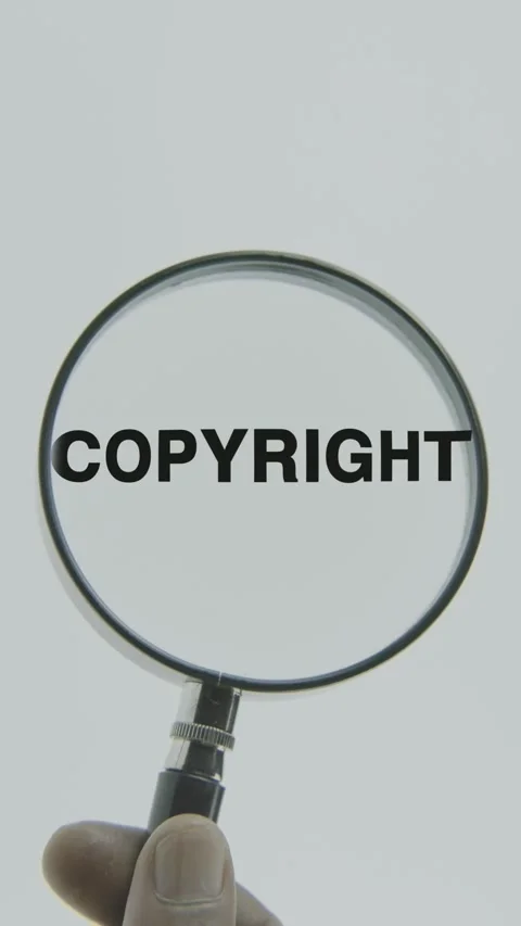 Copyright text or word highlighted by a magnifying glass in a hand Stock Footage 303424805