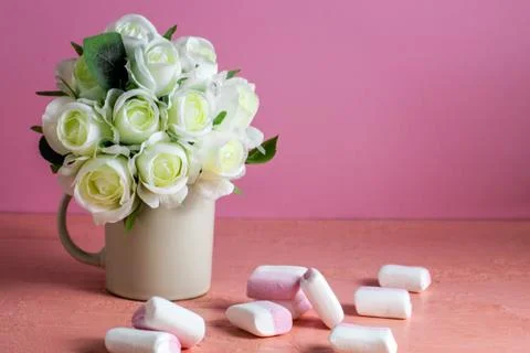 Copyspace with colorful mini marshmallows on a table next to white roses on a Foto stock