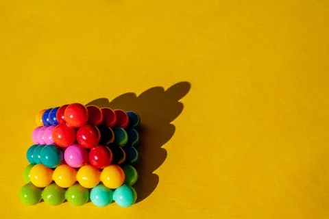Copyspace pyramid of multi-colored bright plastic parts with shadow on yellow Stock Photos