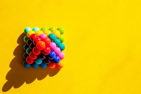 Copyspace pyramid of multi-colored bright plastic parts with shadow on yellow Stock Photos