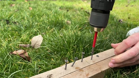 Cordless drill driver is driving a screw into a wooden beam. Stock Footage 346721170