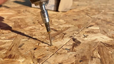 Cordless drill driving large screw into OSB board Stock Footage 346709993