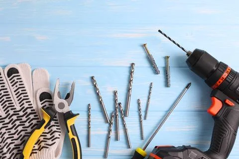 Cordless Drill Featuring Various Drill Bits Set Against a Vibrant Blue Stock Photos