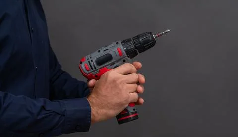 Cordless drill held in single hand against dark studio background, drill to.. Fotos Stock