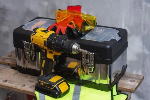 Cordless drill with tool box with protective gloves and safety goggles. Conce Stock Photos