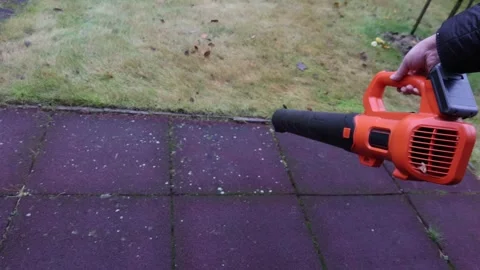 Cordless leaf blower clearing leaves from rubber play surface, right side view Stock Footage 326965634