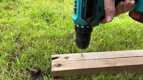 Cordless power drill is drilling a hole into wooden board or beam. Stock Footage 346720860