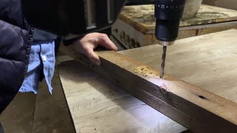 Cordless power drill is drilling a hole into wooden board or beam. Stock Footage 346721101