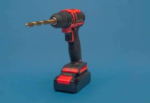 A cordless screwdriver with a drill bit. on the blue. Stock Photos