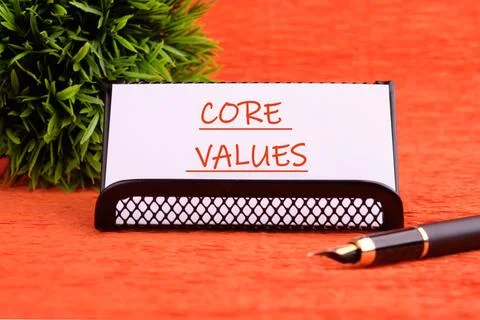 CORE VALUES word written on a white card on a stand on an orange background Stock Photos