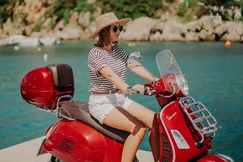 Corfu, Greece - September, 2021. Woman sitting on Vespa scooter motor bike in Stock Photos