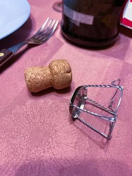 Cork and cage placed on a table with a fork and wine bottle in the background Stock Photos