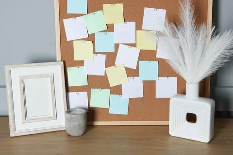 Cork board with blank paper notes and decorative elements on wooden table n.. Stock Photos