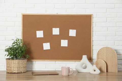 Cork board with blank paper notes, laptop and decorative elements on wooden.. Stock Photos