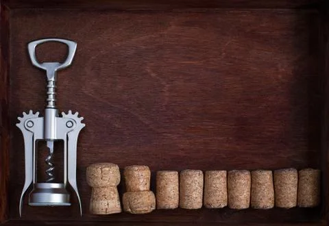 Corkscrew and a row of wine corks into dark box Stock Photos