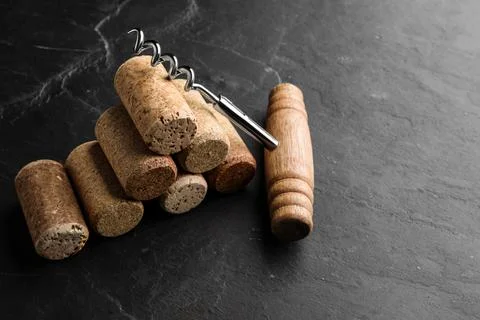 Corkscrew and stack of wine bottle stoppers on slate table 스톡 사진