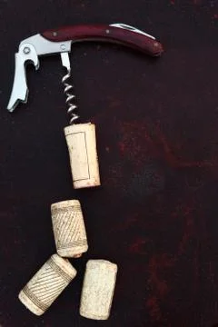 Corkscrew with corks on rusty dark background Stock Photos