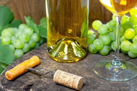 Corkscrew with a crust on the background of a bottle of white wine and grapes 스톡 사진