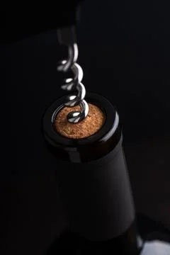 Corkscrew opening a wine bottle with dark background Stock Photos