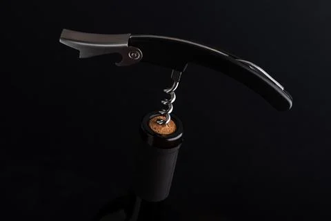 Corkscrew removing cork from a dark wine bottle Stock Photos