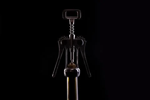 A corkscrew stands on a bottle of wine Stock Photos