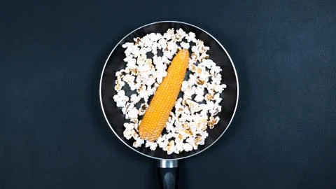 Corn and popcorn in a pan. Black background. Foto stock