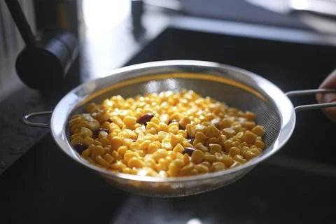 Corn and red beans draining in metal strainer over kitchen sink Stock Photos
