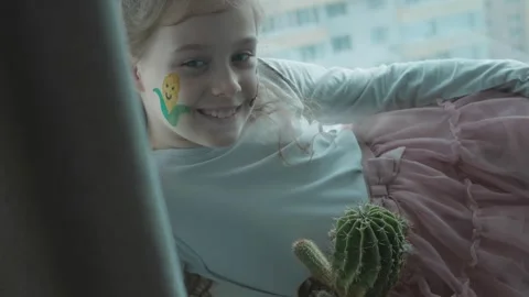 Corn and tractor drawings on the face of a cute cheerful girl. Holding a cactus Stock Footage 256039759