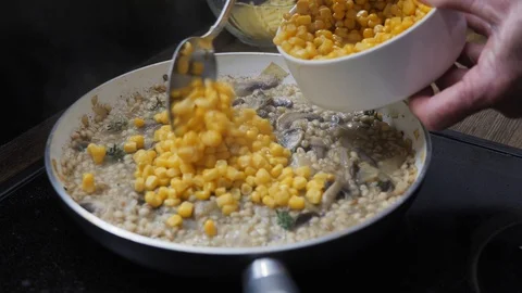 Corn being added to barley risotto with mushrooms Stock Footage 88110992