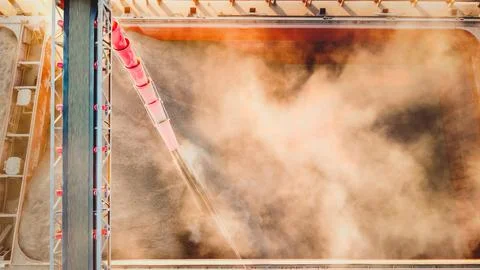 Corn in bulk carrier hold. Casting hold of corn. Elevator crane loads ship bu Фото