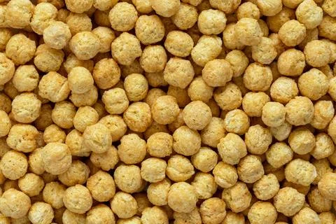 Corn cereal balls texture. Close up view of puffed grain breakfast 库存照片