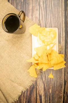 Corn chips with cheese sauce and a coffee mug on a wooden background. Close u Stock Photos