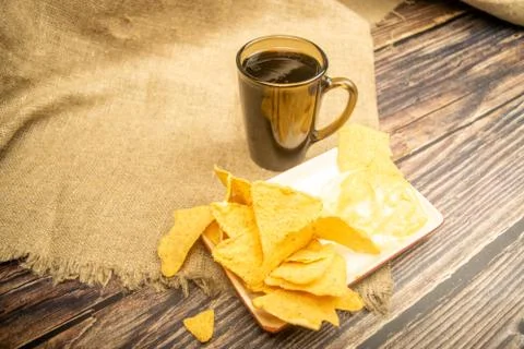 Corn chips with cheese sauce and a coffee mug on a wooden background. Close u Stock Photos