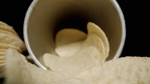 Corn chips, hyperbolic paraboloid in shape, are scattered from a can onto the ta Video stock 260975340