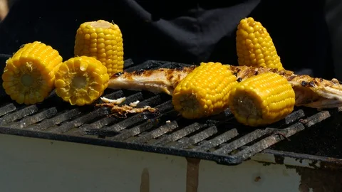 Corn cobs are grilled next to fried fish 스톡 동영상 123582326