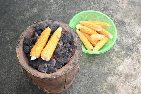 Corn cobs being grilled on a coal stove. Stock Photos