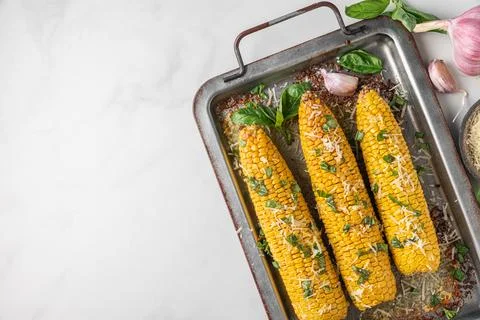 Corn cobs grilled and baked on baking sheet with parmesan cheese and basil .. Stock Photos