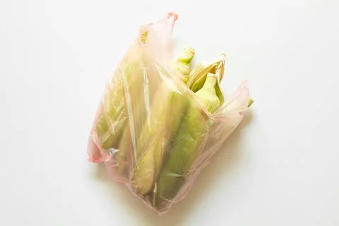 Corn cobs in husk in transparent plastic bag on white background, fresh cor.. Stock Photos