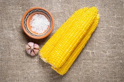 Corn cobs on an old craft dress with a large weaving with salt and bread and Stock Photos