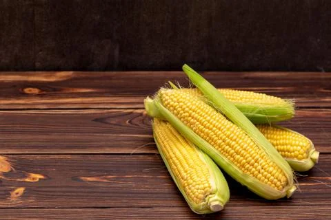 Corn cobs on wooden table. Stock Photos