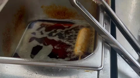 Corn dog deep frying in hot oil Stockbeeldmateriaal 337572322