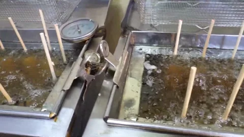 Corn Dogs Frying in Commercial Deep Fryer with Wooden Sticks 動画素材 343587707