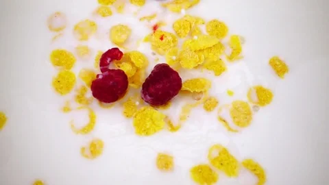 Corn flakes and raspberry fall in the milk in slow motion. 動画素材 101394045