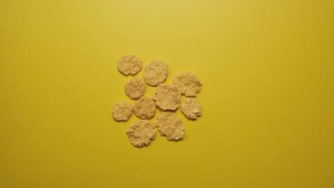 Corn flakes appear and disappear on a yellow background close-up Stock Footage 231791609