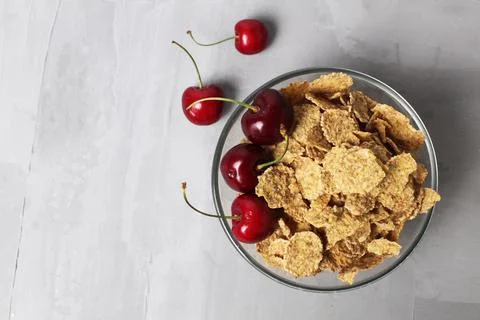 Corn flakes with berries fruit cherries in a bowl plate on a gray background  Stock Photos