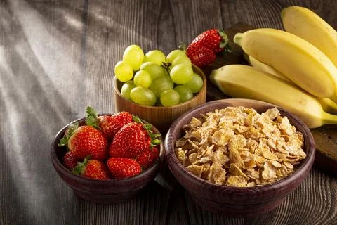Corn flakes in the bowl with berries on the table. Stock Photos