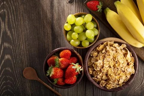 Corn flakes in the bowl with berries on the table. Stock Photos