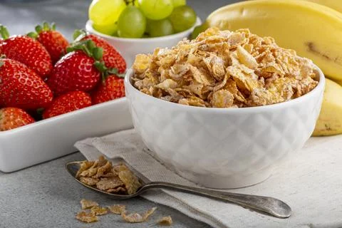 Corn flakes in the bowl with berries on the table. Stock Photos