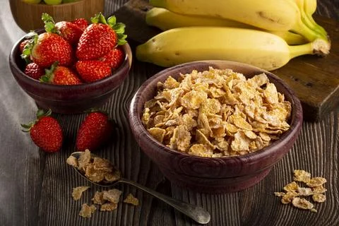 Corn flakes in the bowl with berries on the table. Stock Photos