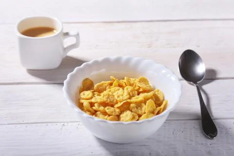 Corn Flakes cereal with milk in a bowl and cap with espresso coffee. Morning Stock Photos